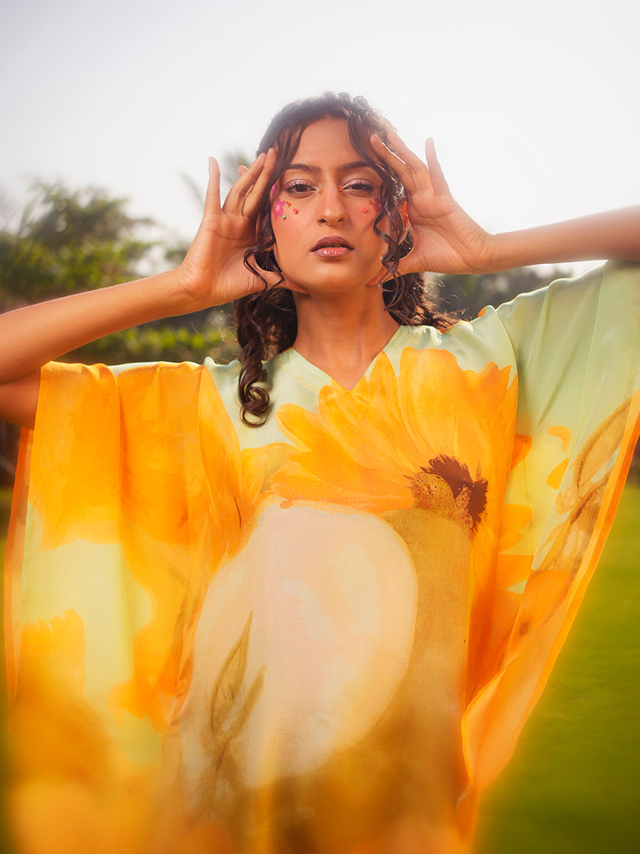 Model wearing pastel green kaftan top with yellow sunflower prints, showcasing the V-neckline and relaxed fit.