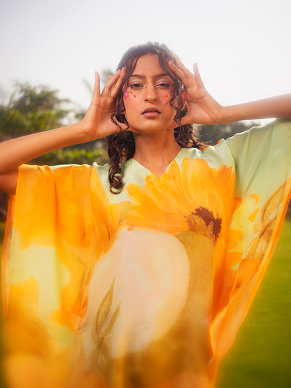 Model wearing pastel green kaftan top with yellow sunflower prints, showcasing the V-neckline and relaxed fit.